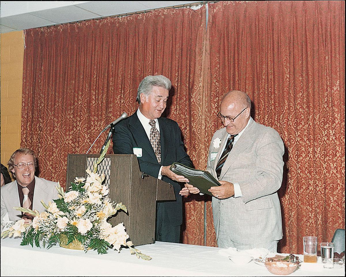 President Foster gives Everett Brown a notebook of letters from friends and colleagues at a retirement dinner in 1976.